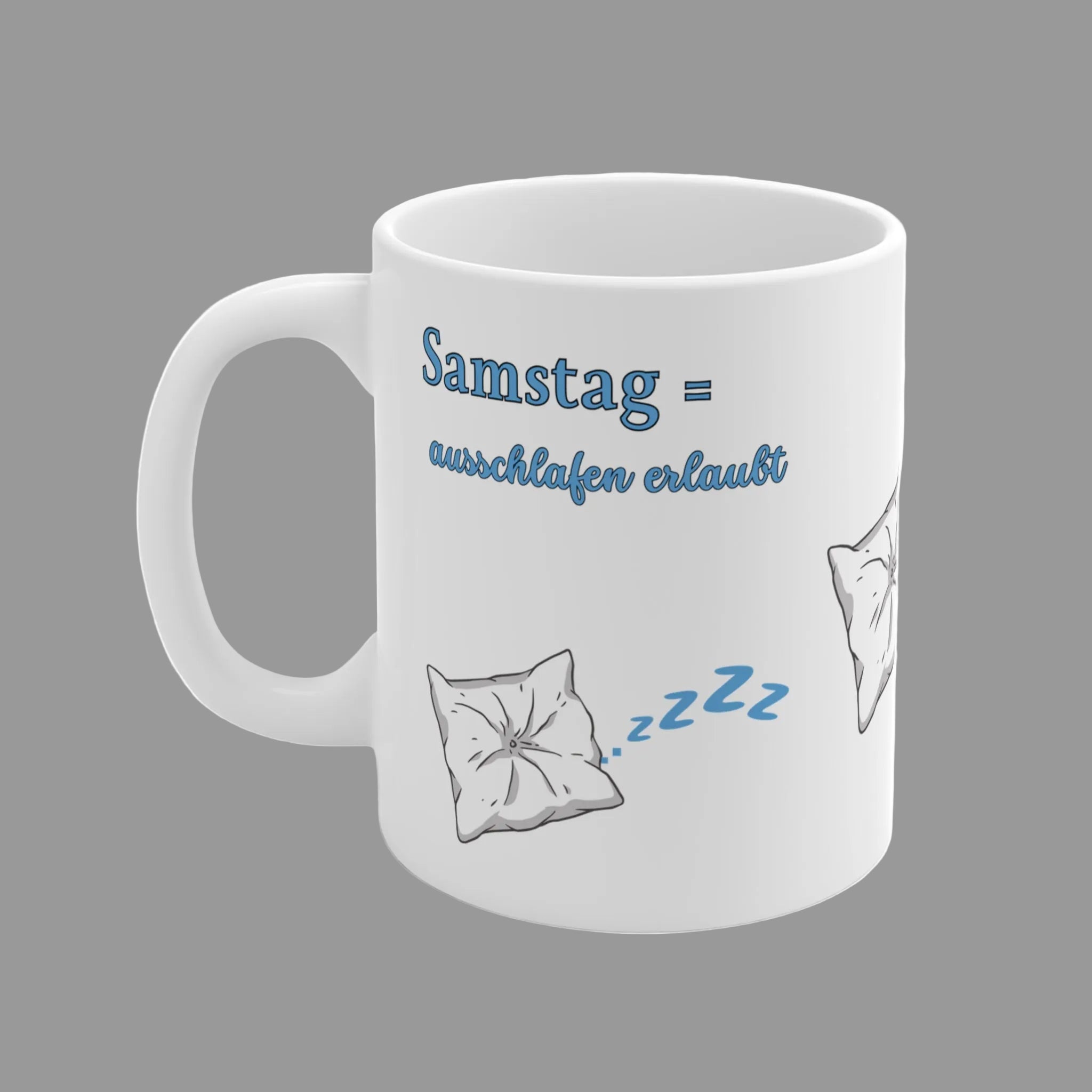 Weiße 300-ml-Keramiktasse mit schlafendem Kissen, blauen "Zzz" und dem Spruch „Samstag = Ausschlafen erlaubt“ – lustige Tasse für Langschläfer und entspannte Wochenenden.