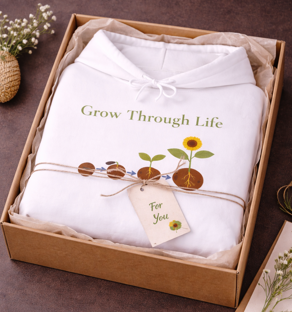 Weißer oder schwarzer Unisex Hoodie mit dem Schriftzug „Grow Through Life“ und einer Illustration vom Samen bis zur blühenden Sonnenblume als Symbol für persönliches Wachstum.