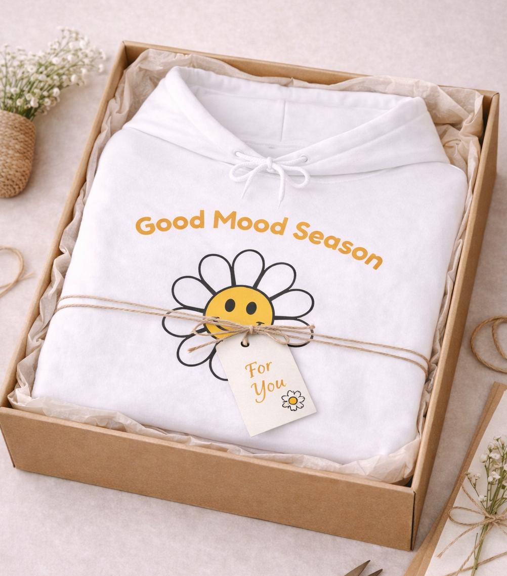 Weißer Unisex-Hoodie mit gelbem Smiley-Blumenmotiv und dem Schriftzug „Good Mood Season“ auf der Vorderseite.