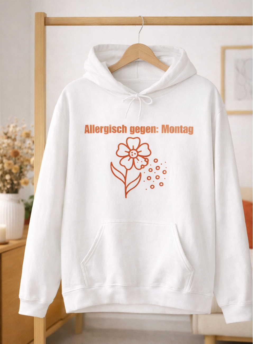 Weißer Unisex-Hoodie mit dem Spruch „Allergisch gegen Montag“ und humorvollem Blumenmotiv mit fliegenden Pollen auf der Vorderseite.