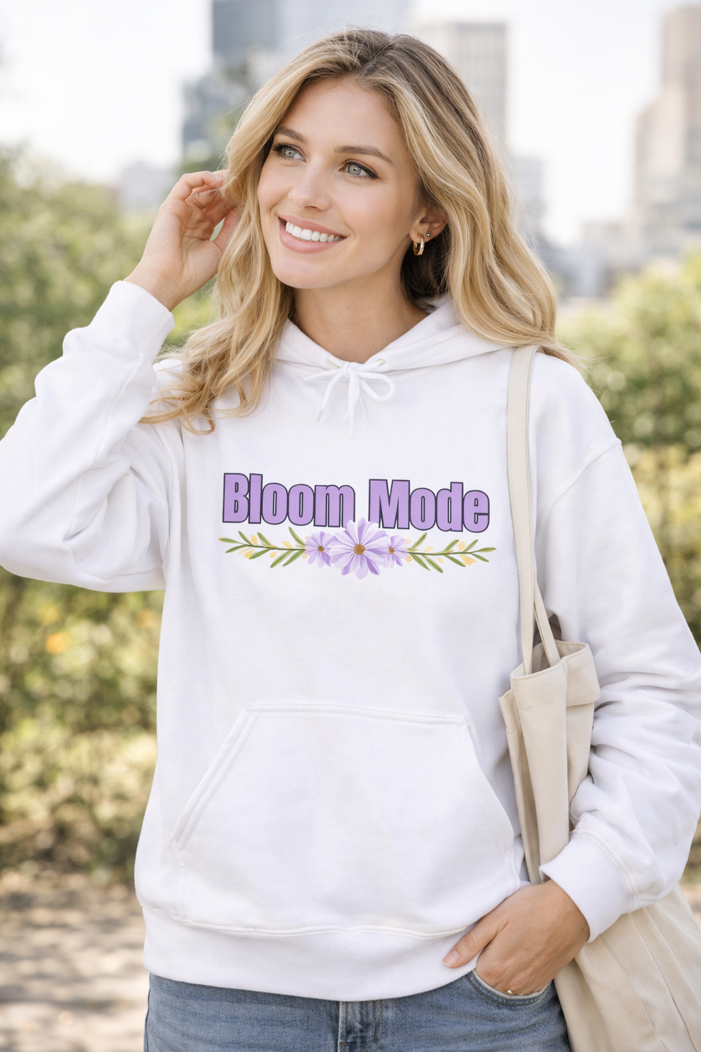 Weißer Unisex-Hoodie mit dem Schriftzug „Bloom Mode“ und einem floralen Blumenmotiv in Lilatönen auf der Vorderseite.