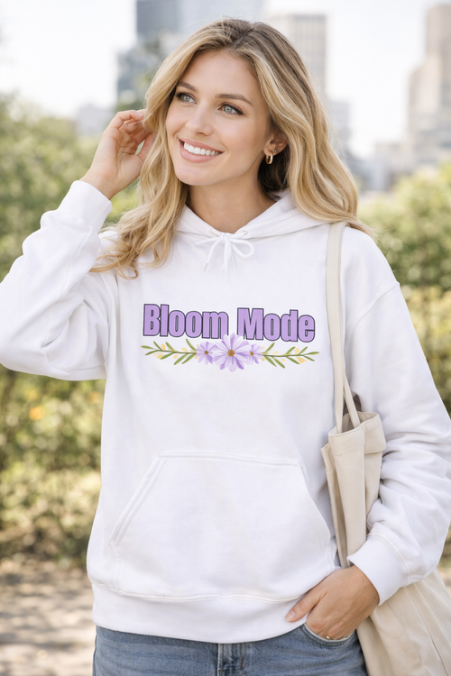 Weißer Unisex-Hoodie mit dem Schriftzug „Bloom Mode“ und einem floralen Blumenmotiv in Lilatönen auf der Vorderseite.