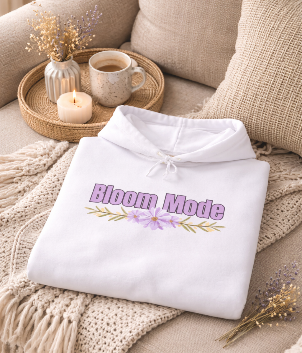 Weißer Unisex-Hoodie mit dem Schriftzug „Bloom Mode“ und einem floralen Blumenmotiv in Lilatönen auf der Vorderseite.