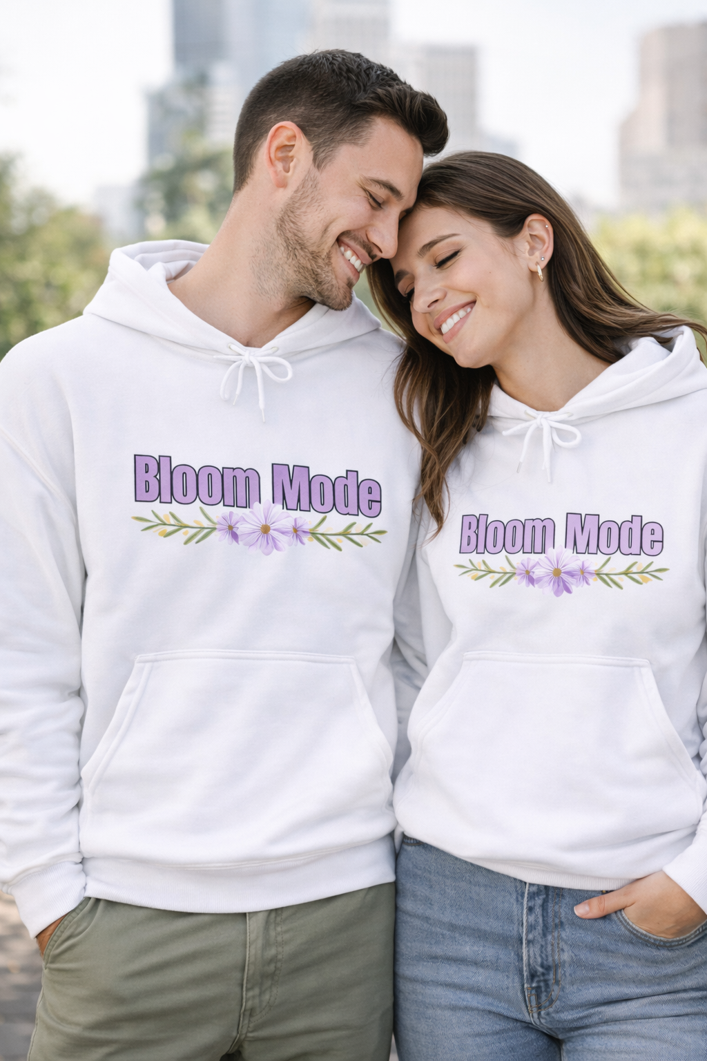 Weißer Unisex-Hoodie mit dem Schriftzug „Bloom Mode“ und einem floralen Blumenmotiv in Lilatönen auf der Vorderseite.