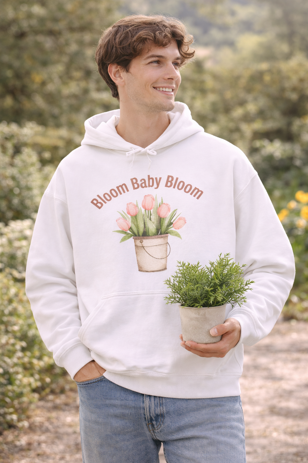Weißer Unisex-Hoodie mit Tulpenmotiv im Blumentopf und dem Schriftzug „Bloom Baby Bloom“ auf der Vorderseite.