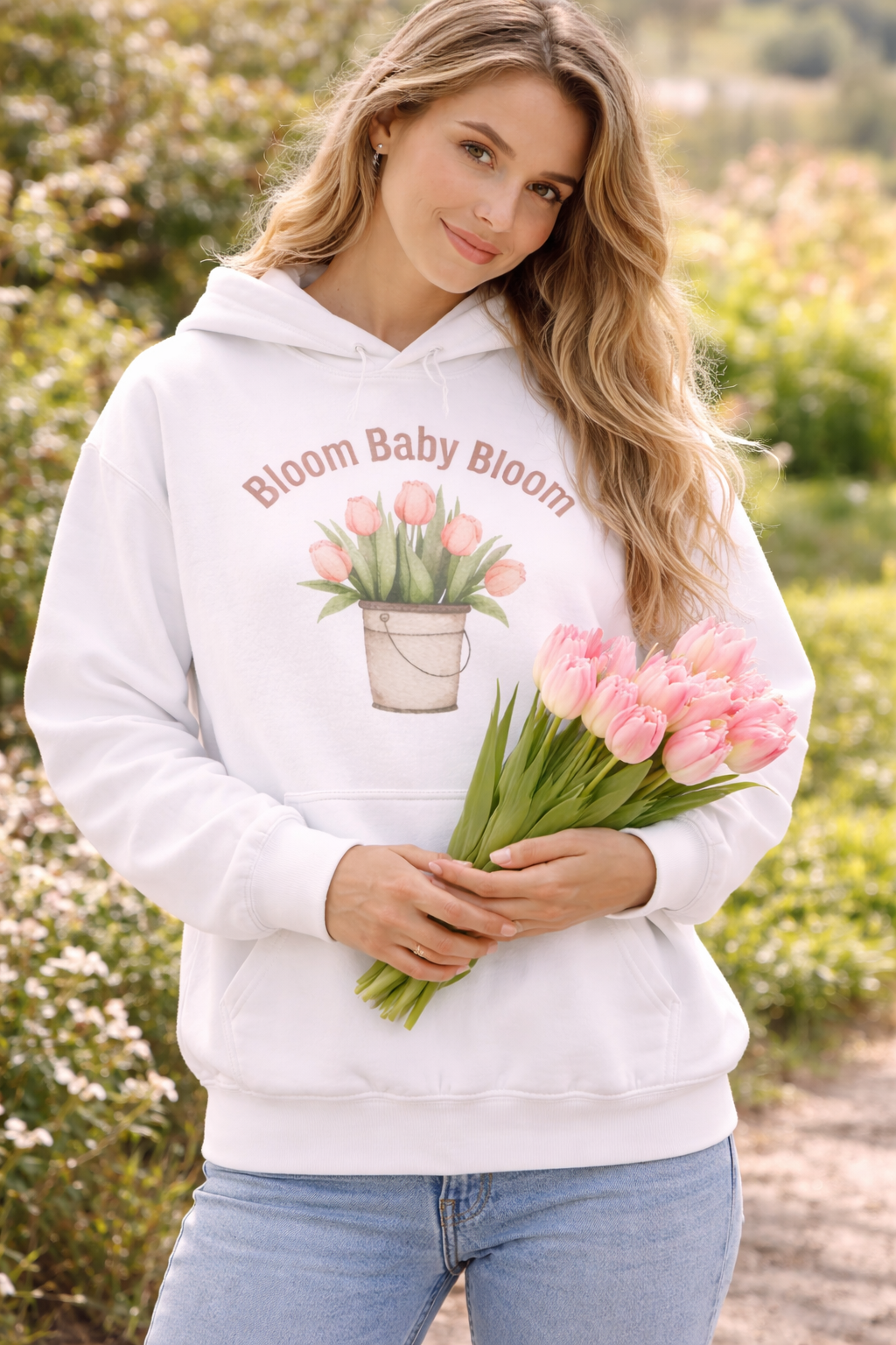 Weißer Unisex-Hoodie mit Tulpenmotiv im Blumentopf und dem Schriftzug „Bloom Baby Bloom“ auf der Vorderseite.