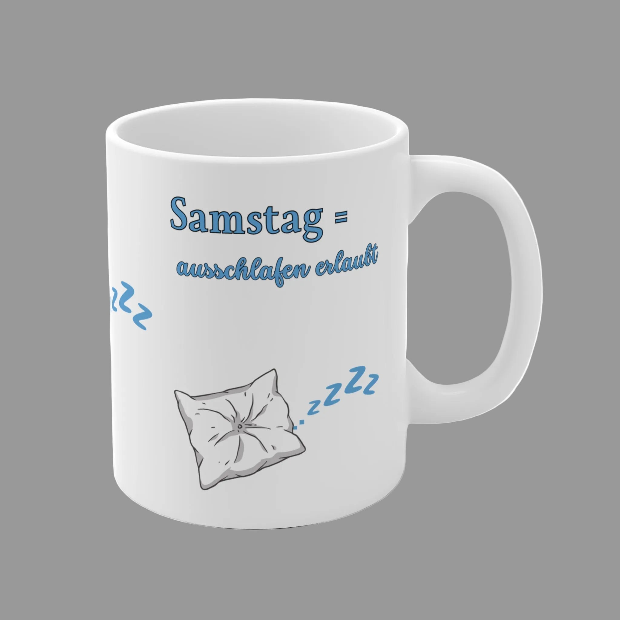 Weiße 300-ml-Keramiktasse mit schlafendem Kissen, blauen "Zzz" und dem Spruch „Samstag = Ausschlafen erlaubt“ – lustige Tasse für Langschläfer und entspannte Wochenenden.