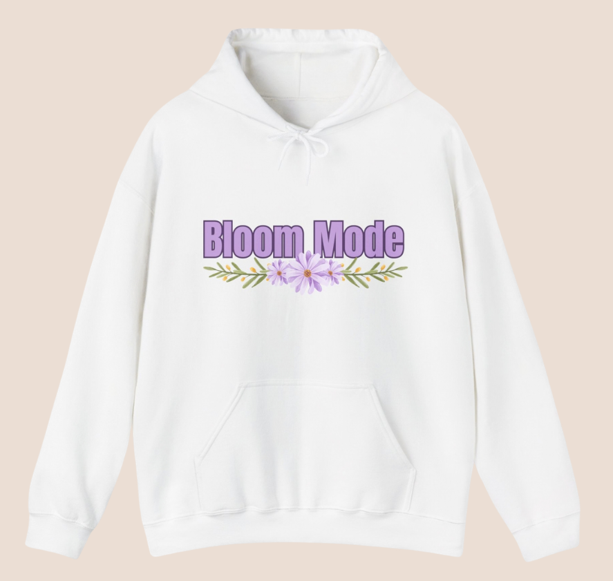 Weißer Unisex-Hoodie mit dem Schriftzug „Bloom Mode“ und einem floralen Blumenmotiv in Lilatönen auf der Vorderseite.