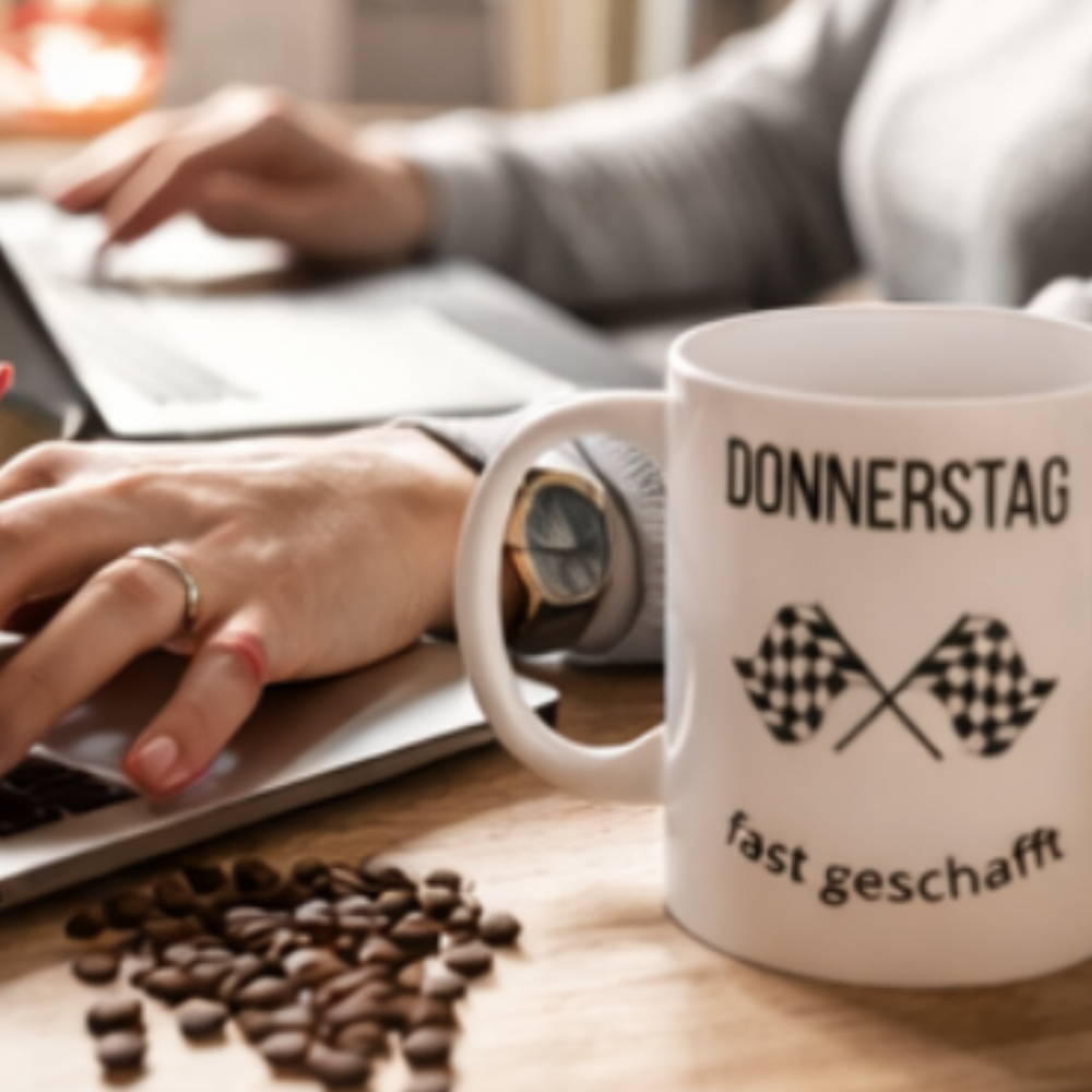 Weiße 300-ml-Keramiktasse mit dem Spruch „Donnerstag fast geschafft“ und zwei schwarz-weißen Zielflaggen – lustige Bürotasse für den Countdown zum Wochenende.