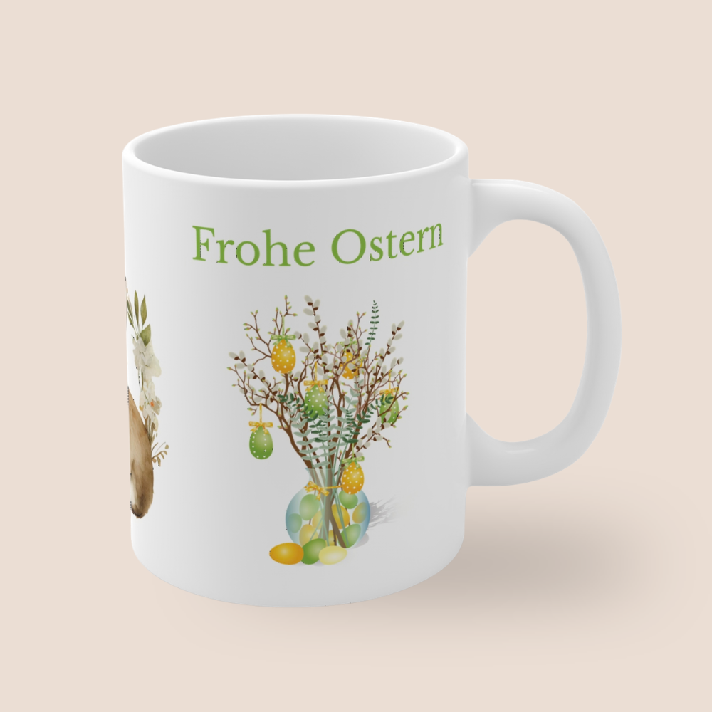 Weiße Keramiktasse mit dem Schriftzug „Frohe Ostern“, einem niedlichen Aquarell-Hasen mit Blumenkranz sowie dekorativen Osterzweigen mit bunten Ostereiern – 300-ml-Ostertasse.