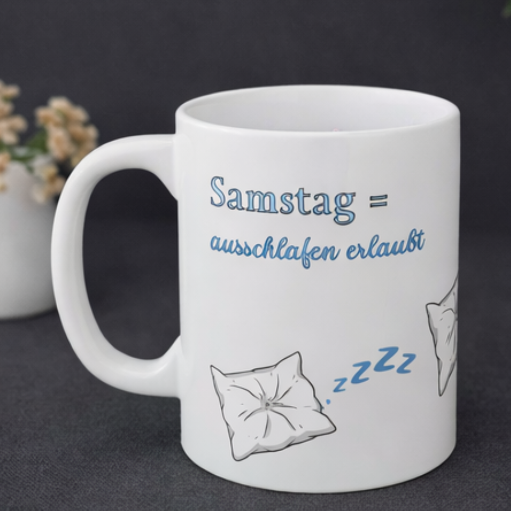 Weiße 300-ml-Keramiktasse mit schlafendem Kissen, blauen "Zzz" und dem Spruch „Samstag = Ausschlafen erlaubt“ – lustige Tasse für Langschläfer und entspannte Wochenenden.