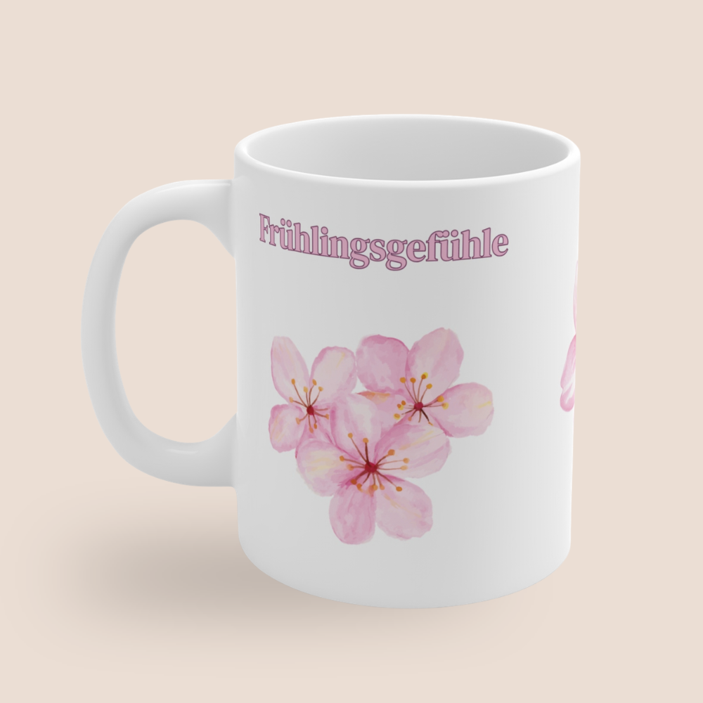 Weiße Keramiktasse mit dem Schriftzug „Frühlingsgefühle“ und zarten rosa Aquarell-Blüten – 300-ml-Tasse mit frühlingshaftem Blumenmotiv.