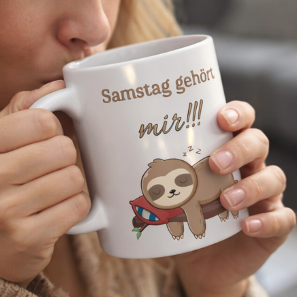 Weiße 300-ml-Keramiktasse mit schlafendem Faultier auf einem Ast und dem Spruch „Samstag gehört mir!!!“ – lustige Tasse für entspannte Wochenenden.