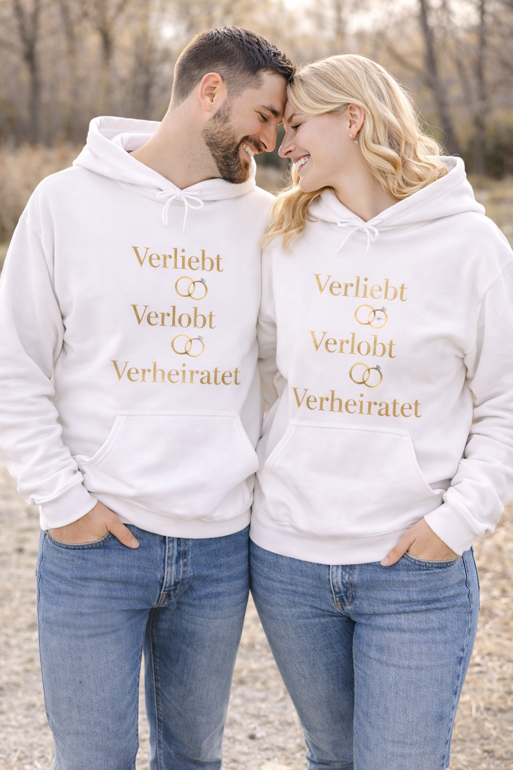 Weißer Unisex Hoodie mit dem eleganten Schriftzug „Verliebt Verlobt Verheiratet“ und dezenten Eheringen – romantischer Hoodie für Paare und Hochzeiten.