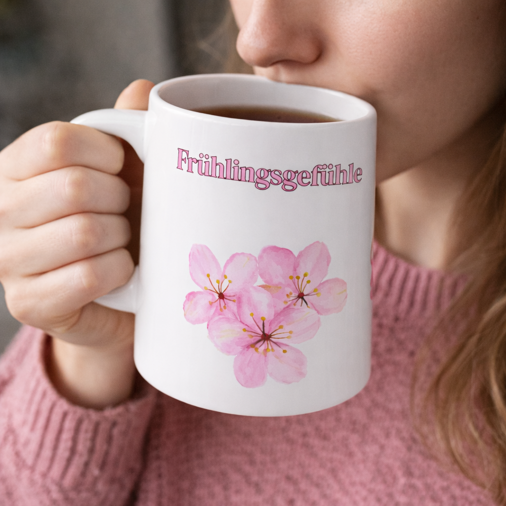 Weiße Keramiktasse mit dem Schriftzug „Frühlingsgefühle“ und zarten rosa Aquarell-Blüten – 300-ml-Tasse mit frühlingshaftem Blumenmotiv.