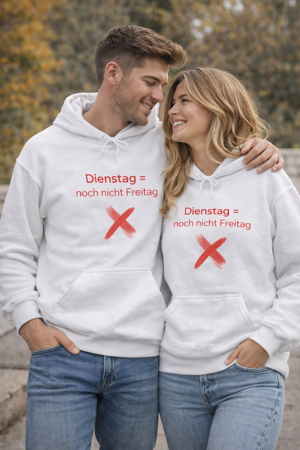 Weißer Hoodie mit dem Spruch „Dienstag = noch nicht Freitag“ und einem roten X als humorvolle Illustration.