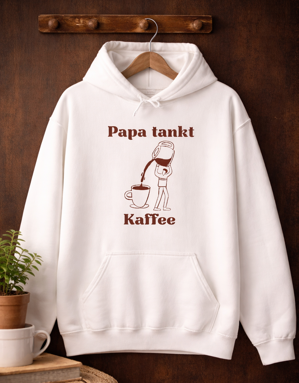 Weißer Hoodie mit dem Spruch „Papa tankt Kaffee“ und einer Illustration einer Kaffeekanne, die Kaffee in eine Tasse einschenkt.