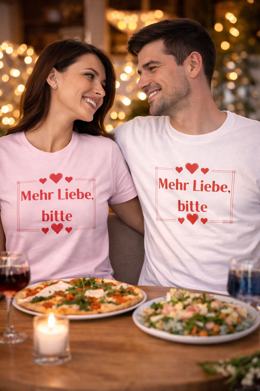 Unisex T-Shirt mit dem Schriftzug „Mehr Liebe, bitte“, dekorativen Herzen und schlichtem romantischem Design in Rot auf weißem oder rosafarbenem Shirt.