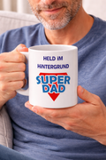 Weiße Keramiktasse mit dem Schriftzug „Held im Hintergrund“ und „Super Dad“ im Superhelden-Stil – 300-ml-Tasse als Geschenk für Papa.